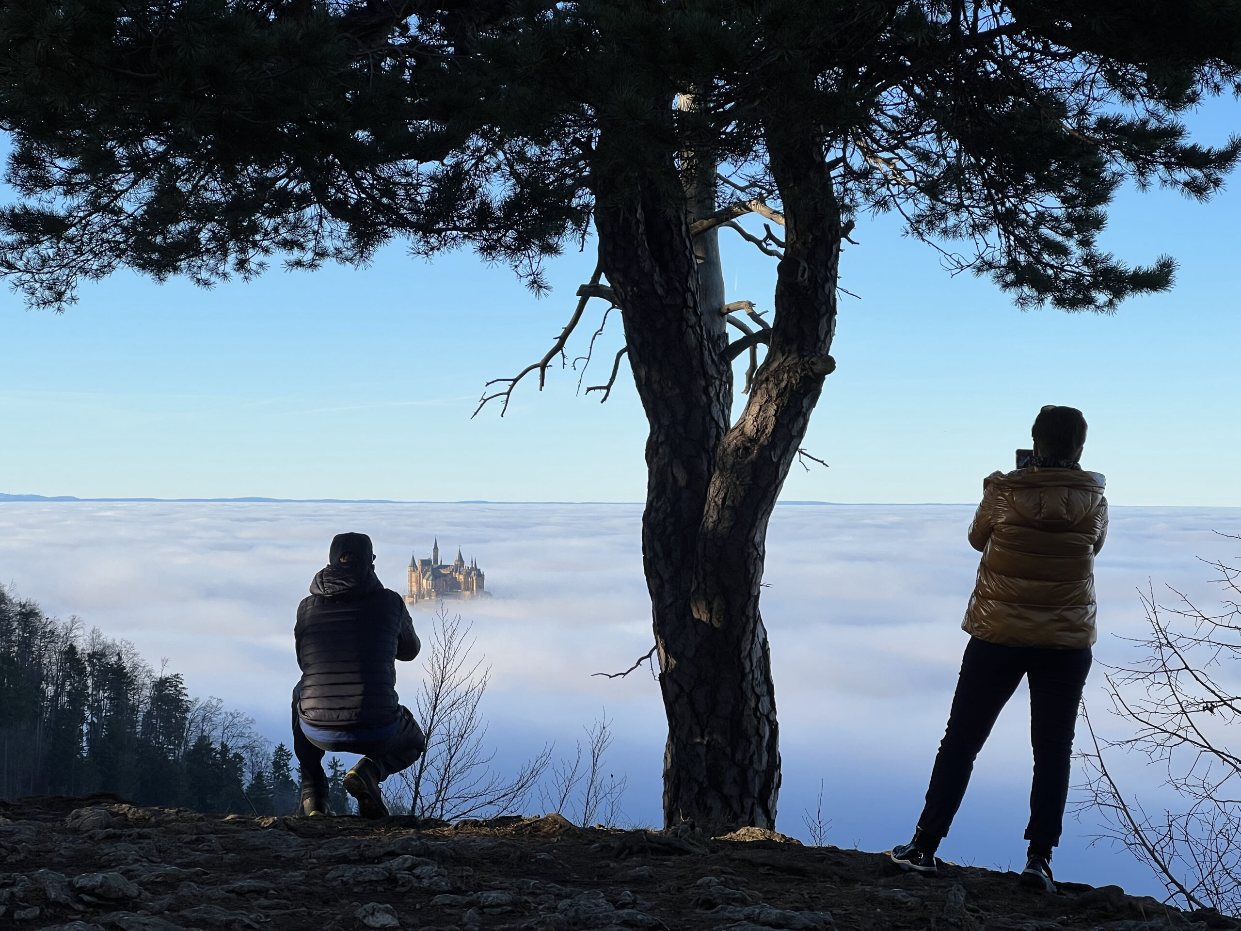 Touristen Blicken auf die knapp über den Wolken stehende Burg Hohenzollern.